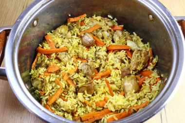 Рассыпчатый плов с курицей в кастрюле на плите